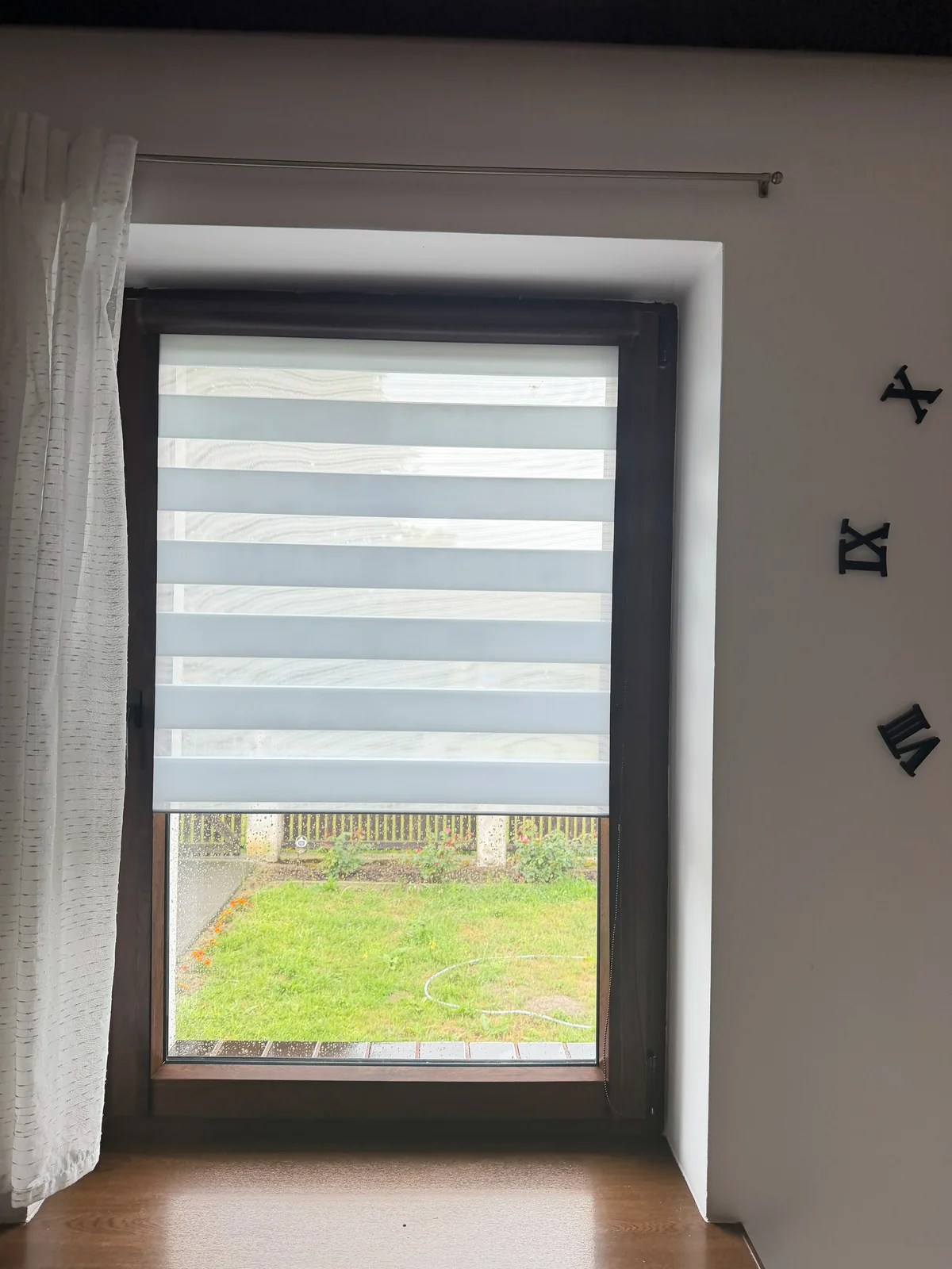 Rolety dzień-noc Szczecin Jasna roleta dzień-noc na pojedynczym oknie z widokiem na trawnik